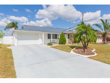 Charming single-story home featuring a well-manicured lawn, driveway, and attached garage under a sunny sky at 907 La Jolla Ave, Sun City Center, FL 33573