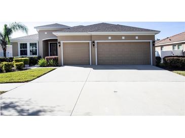 Tan two-story house with two car garage and lush landscaping at 2117 Valterra Vista Way, Valrico, FL 33594