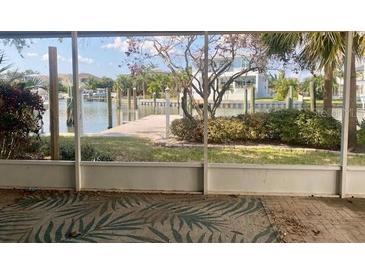Screened lanai view of backyard leading to a waterfront with private dock in a tropical setting at 1943 Bayou Grande Ne Blvd, St Petersburg, FL 33703
