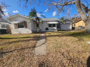 Single-story home with attached garage, mature trees, and a walkway at 469 80Th Way, St Pete Beach, FL 33706