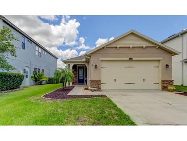 Tan one-story house with two-car garage and landscaping at 29167 Perilli Pl, Wesley Chapel, FL 33543