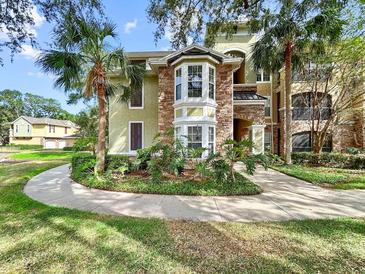Attractive condominium exterior with stone accents, bay window, and mature landscaping with palm trees at 10108 Courtney Oaks Cir # 203, Tampa, FL 33619