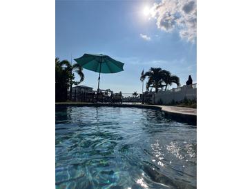 Inviting waterfront pool area featuring lounge chairs and picturesque views of the serene bay at 514 161St Ave, Redington Beach, FL 33708