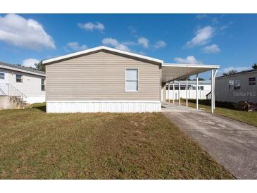 Tan mobile home with carport and paved driveway at 38029 Leondias Dr, Zephyrhills, FL 33542