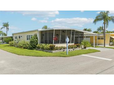 Mobile home with covered porch, landscaped yard, and screened patio at 18675 Us Highway 19 N # 488, Clearwater, FL 33764