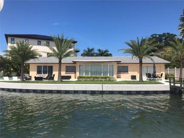 Waterfront home featuring an outdoor seating area, dock access, and lush palm trees in a desirable waterfront location at 239 Punta Vista Dr, St Pete Beach, FL 33706