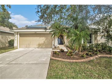 Tan one-story house with a two-car garage, landscaping, and solar panels at 6232 French Creek Ct, Ellenton, FL 34222