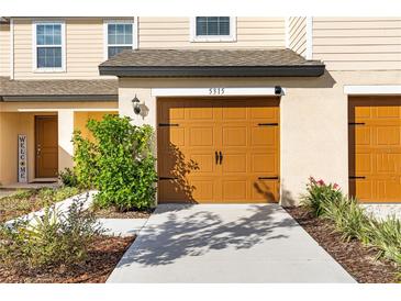 Two-car garage with tan doors and walkway at 5315 Companion Ln, Tampa, FL 33619