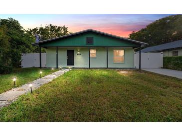 Charming light green single-story home with a green trimmed roof and walkway at dusk at 1013 E 28Th Ave, Tampa, FL 33605