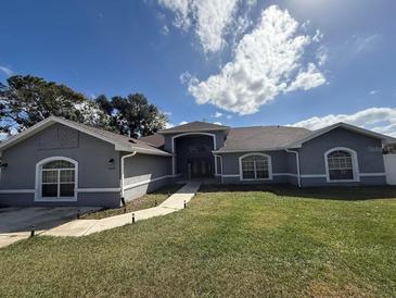 Charming single-story home with arched windows, walkway, and a well-manicured lawn at 15272 Spinning Wheel Ln, Brooksville, FL 34604