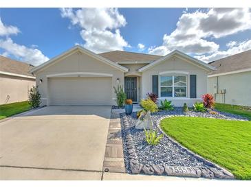 Modern house exterior with a two-car garage, well-manicured lawn, and attractive landscaping at 555 Calico Scallop St, Ruskin, FL 33570