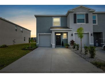 Two-story townhome with gray exterior, two-car garage, and landscaping at 16701 Maude Dr, Wimauma, FL 33598