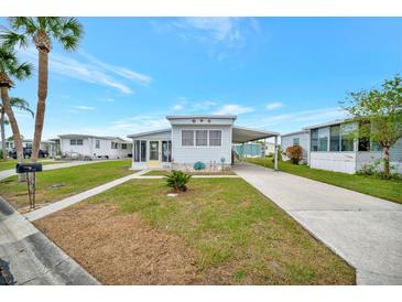 Cute light blue manufactured home with carport and landscaped lawn at 122 E Saint Johns Way, Apollo Beach, FL 33572