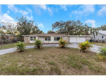 Ranch-style home with attached two-car garage and palm trees at 615 16Th Nw St, Largo, FL 33770