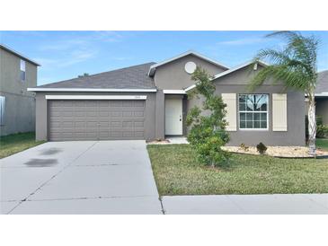 Gray house with a two-car garage and landscaped lawn at 7231 Somerset Pond Dr, Ruskin, FL 33573