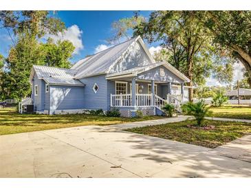 Charming light blue house with a metal roof, porch, and a spacious concrete driveway at 106 E Calhoun St, Plant City, FL 33563