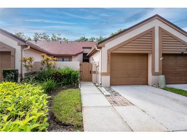 Front view of a charming villa with a two-car garage and landscaped yard at 3454 Hillmoor Dr, Palm Harbor, FL 34685