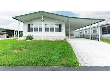 Single-wide manufactured home with carport and well-maintained lawn at 37617 Amigo Dr, Zephyrhills, FL 33541