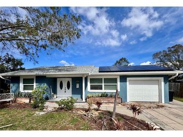 Blue house with solar panels, white garage door, and landscaping at 311 80Th Ne Ave, St Petersburg, FL 33702