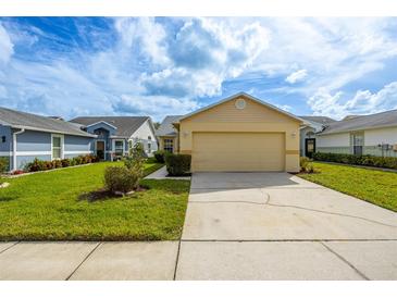 Tan house with a 2-car garage and manicured lawn at 6322 Gentle Ben Cir, Wesley Chapel, FL 33544