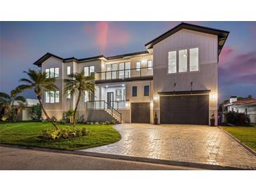 Elegant two-story home with a paved driveway, lush lawn, and a three-car garage at twilight at 1954 Iowa Ne Ave, St Petersburg, FL 33703