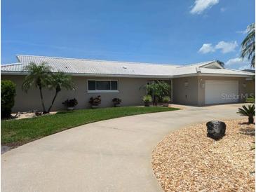 Spacious single-story home with a white tile roof, manicured lawn, and circular driveway at 212 Poinciana Ln, Largo, FL 33770