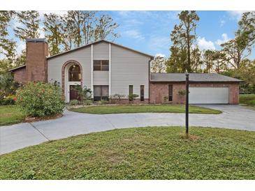 Two story house with brick and siding, attached garage, and landscaped lawn at 223 S Riverhills Dr, Temple Terrace, FL 33617