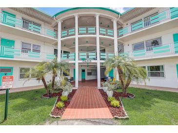 Oasis community building, featuring a teal and white color scheme, palm trees, and a walkway at 1900 59Th N Ave # 305, St Petersburg, FL 33714