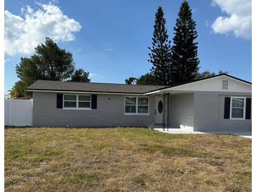 Newly renovated house featuring gray brick exterior, and a well-manicured lawn at 2643 Almond Dr, Holiday, FL 34691