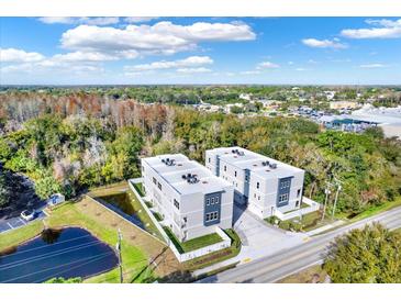 Aerial view of two modern townhouses near a pond and road at 3845 Seena Manor Ct, Tampa, FL 33618