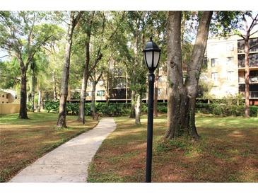 Picturesque community grounds with walking path, mature trees, and manicured landscaping at 3076 Eastland Blvd # 106, Clearwater, FL 33761