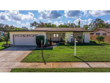 Ranch-style home with attached garage and lawn at 1585 Idle Dr, Clearwater, FL 33756