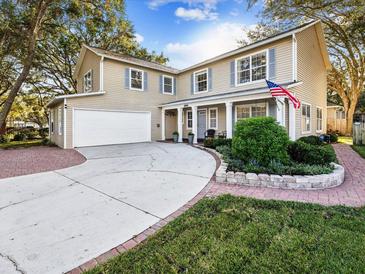 Two-story house with a large driveway, landscaped yard, and American flag at 4410 Serenity Trl, Palm Harbor, FL 34685