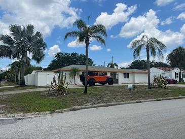 Single-story home with a white exterior, palm trees, and a driveway at 1017 Robinson N Dr, St Petersburg, FL 33710