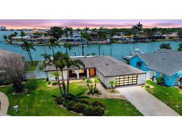 Inviting waterfront home featuring lush landscaping, a modern garage door, and serene water views at 11683 Grove St, Seminole, FL 33772
