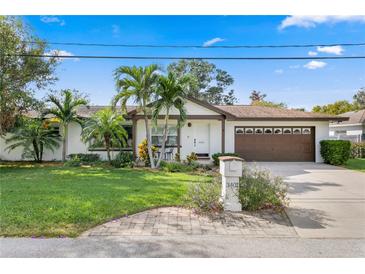 White single-story home with brown roof, palm trees, and landscaped lawn at 3401 W North B St, Tampa, FL 33609