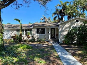 Charming light beige house with landscaped yard and walkway at 909 35Th N St, St Petersburg, FL 33713