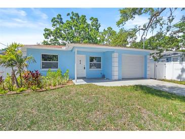 Charming, light blue single-story home with an attached garage and a well-manicured front lawn at 615 W Virginia Ave, Tampa, FL 33603