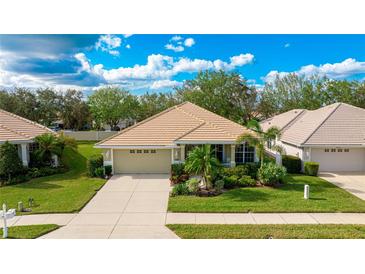 One-story home with a beige exterior, tile roof, and well-manicured lawn at 2681 Whispering Pine Ln, North Port, FL 34287