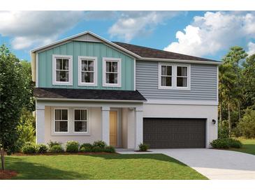 Two story home with teal and gray siding, dark garage door, and landscaping at 12136 Cattleside Dr, Riverview, FL 33579