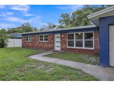 Brick ranch home with blue accents and a well-maintained lawn at 12905 N Oregon Ave, Tampa, FL 33612
