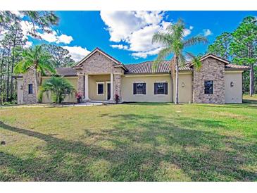 Tan house with stone accents, tile roof, and palm trees at 5403 Golddust Rd, Spring Hill, FL 34609