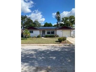 Charming ranch-style home featuring a well-maintained front yard and solar panels at 8906 Windsong Ln, Port Richey, FL 34668