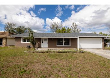 Charming single-story home featuring a gray roof, brown siding, and an attached two-car garage at 1505 New Bedford Dr, Sun City Center, FL 33573