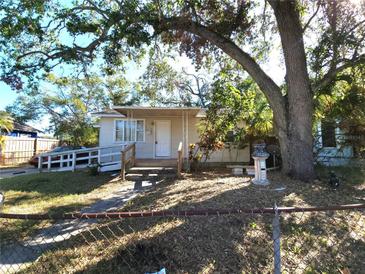 Tan house with white trim, ramp, and mature trees in the front yard at 1708 Preston S St, St Petersburg, FL 33712