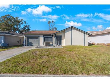 Charming single story home with a well-manicured lawn and attached garage at 1722 W Groveleaf Ave, Palm Harbor, FL 34683