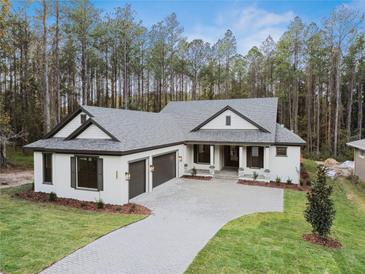 Two-story house with gray roof and three-car garage at 19504 Sheltered Hill Dr, Brooksville, FL 34601