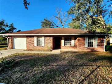 Brick ranch home with a single car garage and mature trees at 20054 Us Highway 301, Dade City, FL 33523