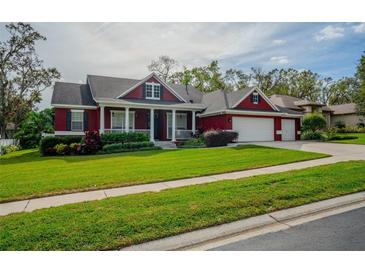Beautiful red house with a large front yard, two-car garage, and well-manicured lawn at 511 Crowned Eagle Ct, Valrico, FL 33594