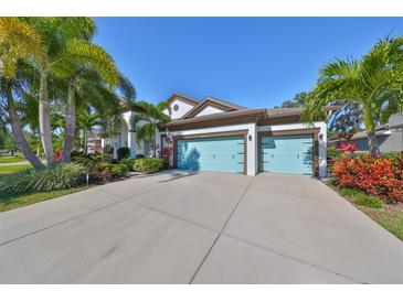 Two-story house with a three-car garage, lush landscaping, and a large driveway at 6646 Park Strand Dr, Apollo Beach, FL 33572